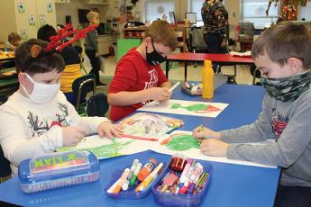 Press photo/Jake Browning - Students in Crystal Teem’s first-grade class at South Macon Elementary School wear their masks while they work on a Grinch-themed coloring project. From left: Liam Long, Austin Trivett and Rylan Armstrong.