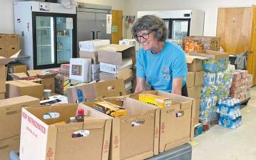 Press photo/Mia Overton - A CareNet volunteer helps prepare boxes of food for people to pick up at the Bidwell Street location.