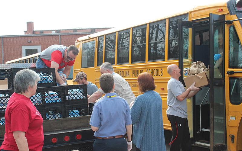 Press photo/Jake Browning - Volunteers at Franklin High School load breakfasts and lunches onto a bus to deliver to local students.