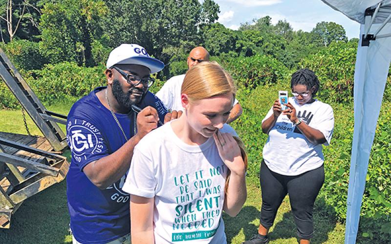 Allen W. Brown, a Christian rapper and evangelist, signs Carissa McGaha’s shirt during the Aug. 30 Save the Children event in Franklin. 