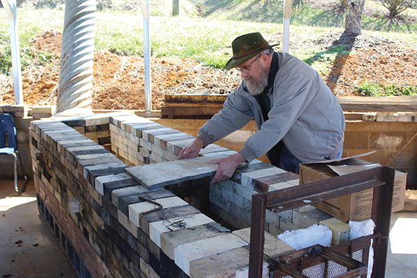 Press photo/Jake Browning - Doug Hubbs, an instructor at the Cowee Pottery School, works on putting together the school’s wood kiln on weekends.