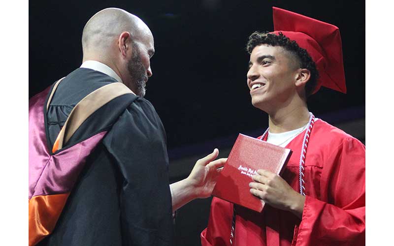 Press photo/Shelby Powell - Franklin High School graduate Samuel Roots accepts his diploma from Principal Blair King during the commencement ceremony June 5 at WCU. Roots wears a braided cord symbolizing his achievements in project management. See more photos on page on The Franklin Press Facebook page. 