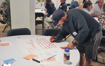 Press photo/Shelby Powell - Cory Spychalski of The Grove Hostel writes out a draft visioning statement for Franklin identifying its recreation, arts and culture as a draw for the town.