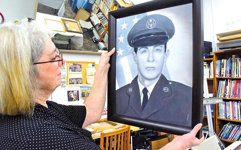 Press photo/Linda Mathias Karen Smith, chair of the Macon County Art Association’s Veterans Portraits program, unwraps a portrait of Air Force veteran Robert Lethbridge on Wednesday at the Uptown Gallery.
