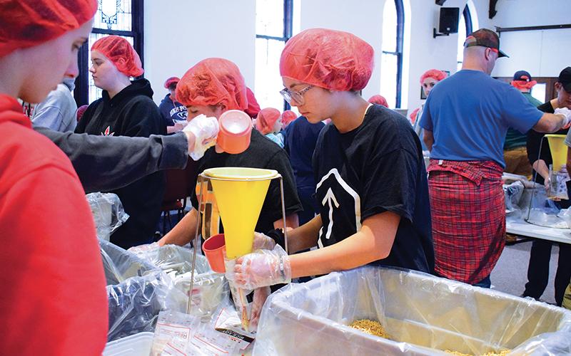 Press photos/Linda Mathias - Volunteers pack rice, soy, vegetables and vitamins for a Rise Against Hunger food packing drive at First United Methodist Church.