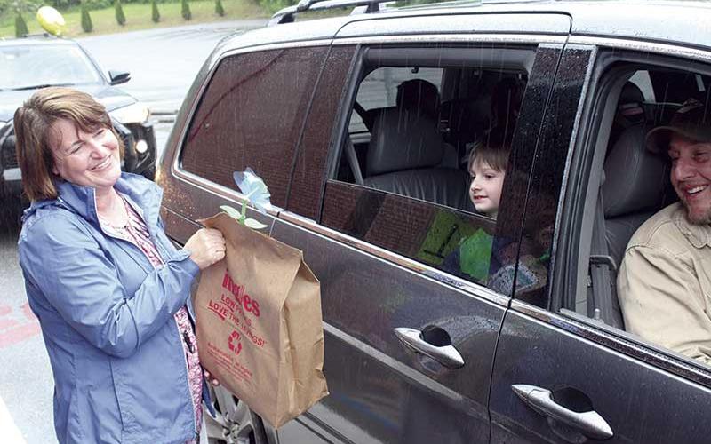 Press photo/Jake Browning - First-grader Lawson Clay, accompanied by his father Jason Clay, picks up his graduation goodie bag from teacher Pam Owens at East Franklin Elementary School’s farewell parade.