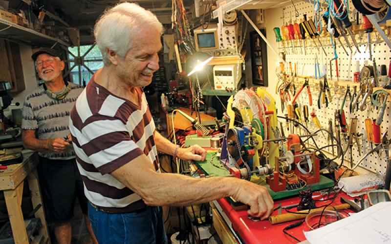 Press photo/Linda Mathias - Andrew Latorre shares a laugh with Tom Tyre as he works on the mechanical Democracy Machine at their home in Otto.