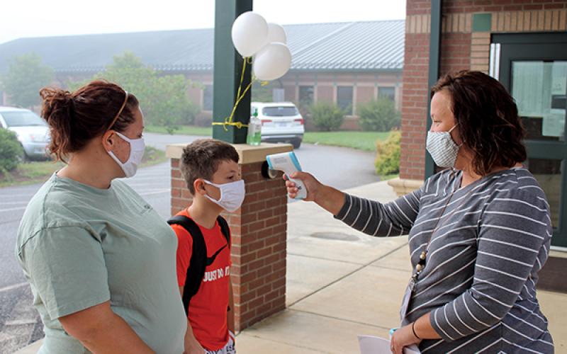 Press photo/Jake Browning - Students and their parents all need to get their temperature checked before entering a school building. From left: Danielle Bryson, sixth-grader Jet Carroll and Mountain View Intermediate School principal Nancy Breedlove