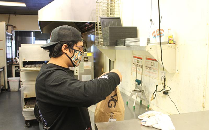 Press photo/Will Woolever - Papa’s Pizza To Go owner Eric Olvera opens a bag of flour while preparing for the day’s service. Olvera does not know whether Papa’s will be allowed to stay in its current location during renovations.
