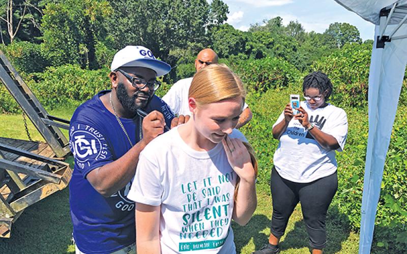 Allen W. Brown, a Christian rapper and evangelist, signs Carissa McGaha’s shirt during the Aug. 30 Save the Children event in Franklin.