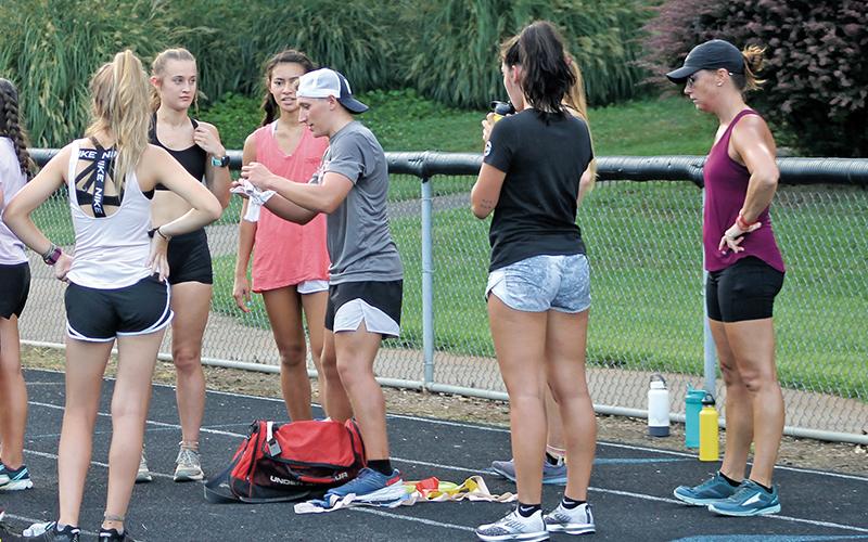 Press photo/Will Woolever Newly named head track and field coaches Kyle Brown (gray shirt, middle) and Melissa Ward (purple shirt, far right) address runners at a recent cross-country practice.