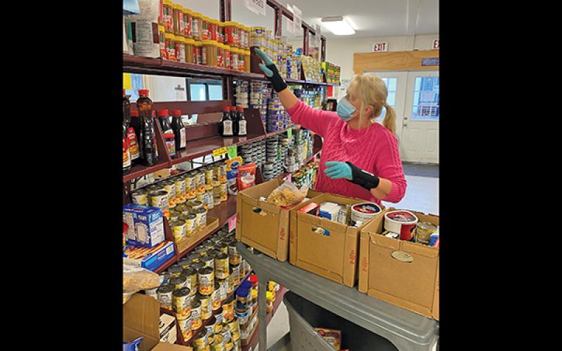Press photo/Jake Browning - Shirl Frantz helps pack boxes of food for clients at CareNet. CareNet also hopes to distribute plenty of warm winter clothes following Cold for a Cause this weekend.