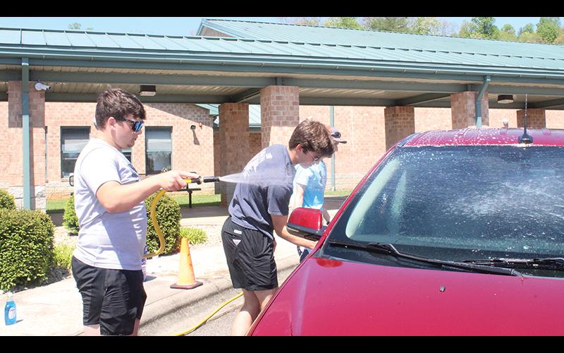 Press photo/Jake Browning - Franklin High School students Gavin Awtrey, Bryce Rogers and Blaine Doolittle wash teachers’ cars at Cartoogechaye Elementary School as part of North Carolina’s Teacher Appreciation Week.