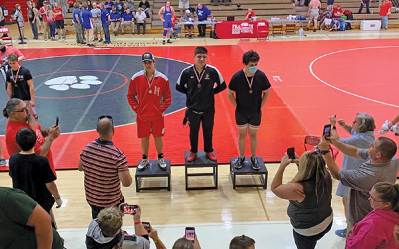 Press Photo/Will Woolever - FHS senior Branden Berger (center) stands on the podium after winning a Mountain Six Conference individual title. Berger will not wrestle at Regionals or State in order to attend basic training in the National Guard.
