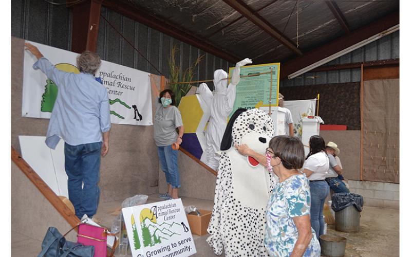 Press photos/Mia Overton - Volunteers with Appalachian Animal Rescue Center work on their booth at the Macon County Fair on Monday morning.