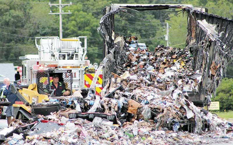 Press photo/Benito Garcia - A fiery collision involving a transfer truck and two vehicles Saturday afternoon closed Georgia Road to through traffic. Three people were transported with injuries. The driver of one of the vehicles faces multiple charges including DWI and reckless driving. Pictured are crews cleaning up after the fire was extinguished.