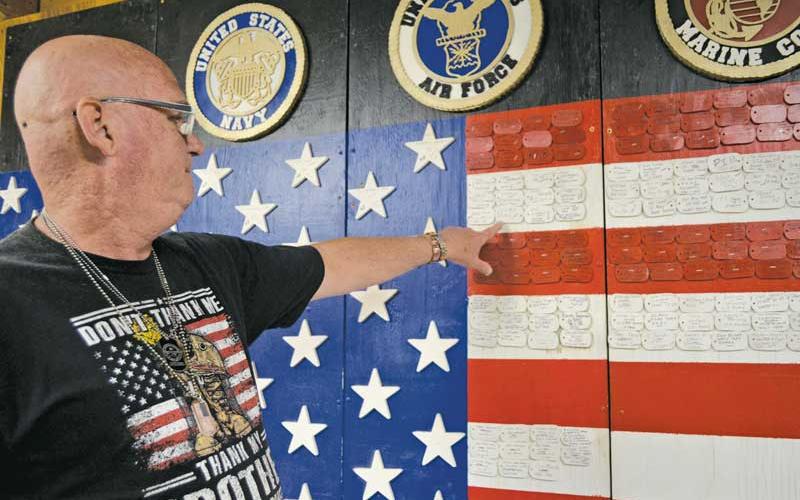 Press photo/Mia Overton - Kenneth Elkins has created a large American flag as a memory wall in tribute to those who have served our country. The stars on the flag represent those who were killed in action or are missing in action.