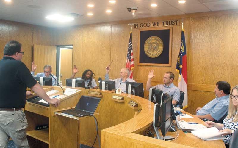 Press photo/Thomas Sherrill - Commissioners Gary Shields, Danny Antoine, Paul Higdon and Josh Young vote for solid waste fee hikes during a special called meeting on Monday, June 26. Commissioner John Shearl, sitting next to Young, voted against the fee increases. Also pictured is Solid Waste Director Chris Stahl (far left) and County Finance Director Lori Carpenter (far right).
