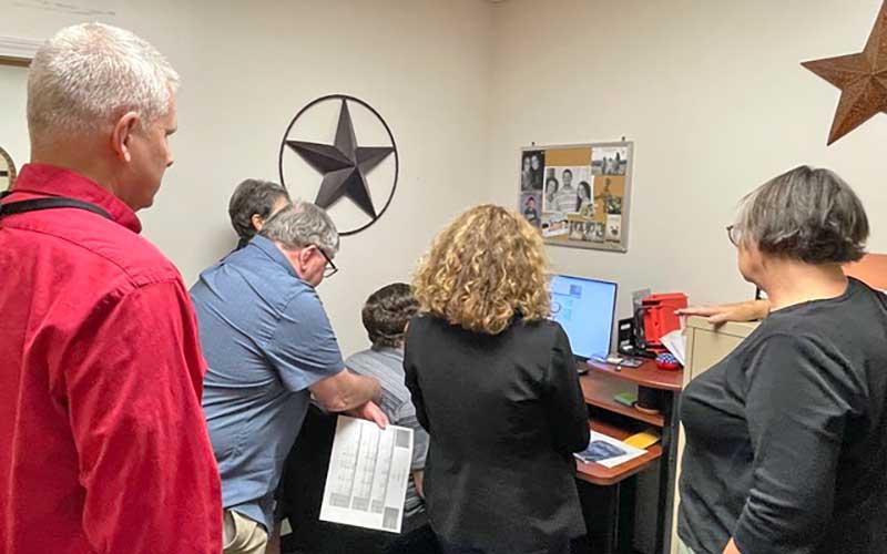 Press photo/Mia Overton - Macon County Board of Elections board members and staff watch the new voting equipment tabulate the ballots on Tuesday night.