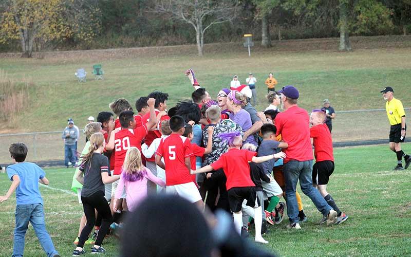 Press photo/Will Woolever - Goalkeeper Drew Hodges (center, wearing goggles) is mobbed by teammates, family and friends after a 10-round penalty shootout versus Polk to clinch a Blue Ridge Athletic Conference title.