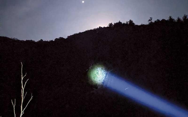 Photo submitted - A spotlight shines on the area where the man was located. This photo was taken at about 4:30 a.m. – the moon is just below the horizon and the dot that looks like a star is the Macon County drone that was used in the search and rescue operation.