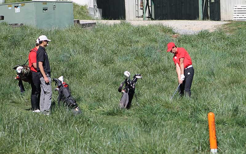 Press photo/Will Woolever - Junior Gabe Stilwell chips out of tall grass at Sky Valley Country Club during Round 1 of the Mountain Seven Conference Tournament April 22. The ball is visible in front of Stilwell’s leg.