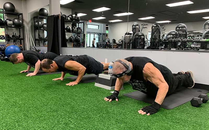 Press photo/Will Woolever - (From left) Stephen Drake, Johnny Lee and Dr. Rocky Battaglino pump out one of their 1,600 pushups for the day at Franklin Health and Fitness.