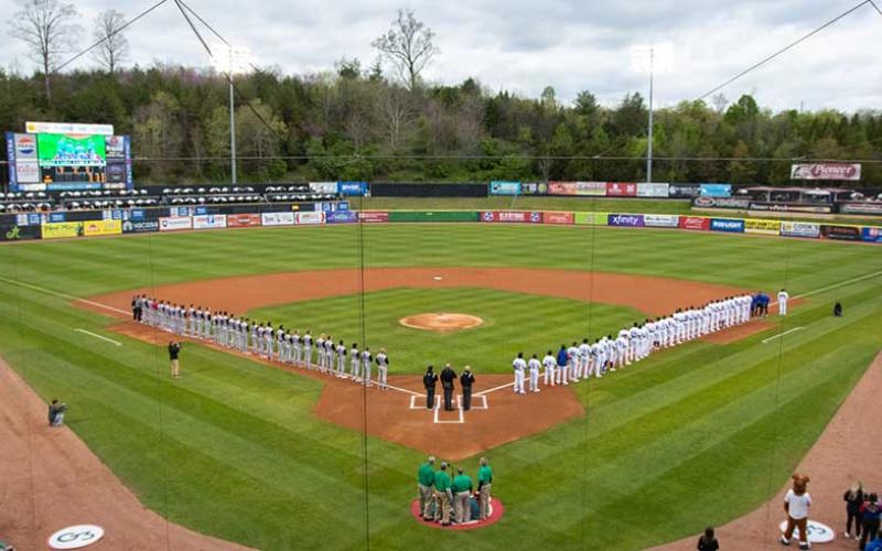 Photo/Tennessee Smokies - The Tennessee Smokies (right) and the Rocket City Trash Pandas (left) stand on the field for the national anthem on opening day, April 5, at Smokies Stadium in Kodak, Tennessee.