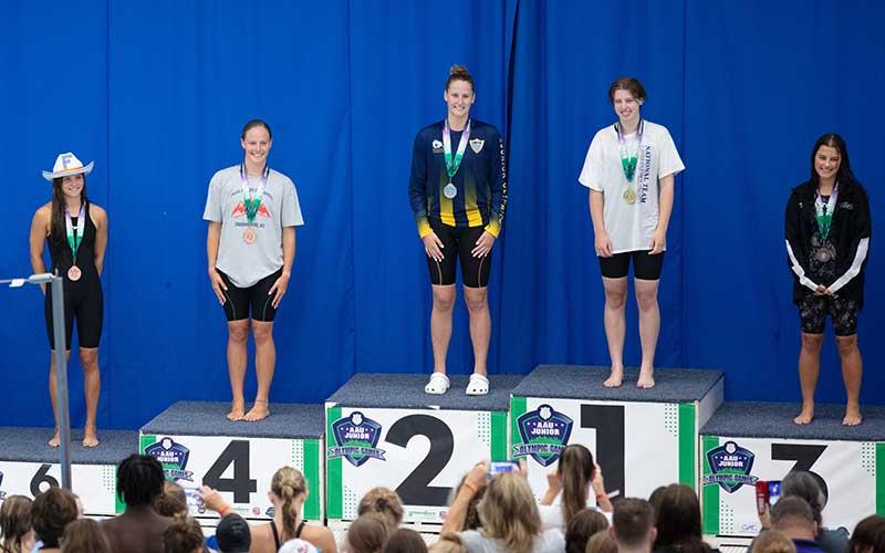 Photo courtesy of Amy Ballard - FAST phenom Claire Ballard is pictured on the podium with her fourth-place medal in the 17-18 girls 50-meter freestyle at the Amateur Athetic Union Junior Olympics in Greensboro last weekend.