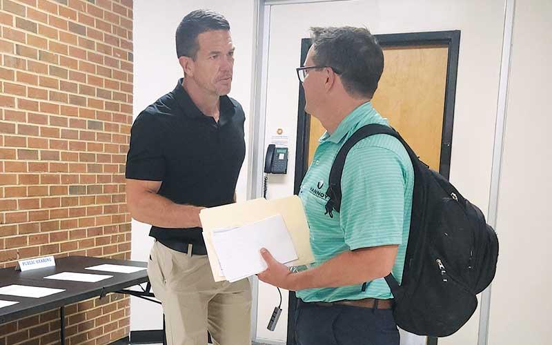 Press photo/Thomas Sherrill - Derek Roland (left) meets a representative of Vannoy Construction minutes before the Sept. 10 Macon County Commissioners’ meeting where he tendered his resignation as county manager.