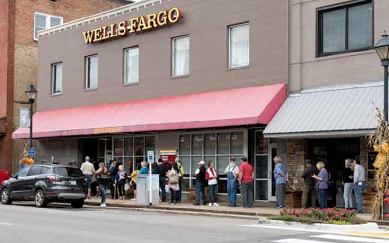Photo/Bob Scott - People wait outside Wells Fargo. Many banks and businesses were offline the first part of the week and could only process cash transactions. As service is restored people will once again be able to use their debit and credit cards.