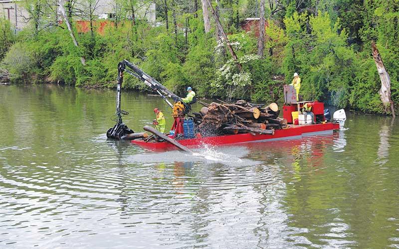 Press photo/Shelby Powell - An Army Corps of Engineers-contracted barge cuts and removes logs from the Little Tennessee River near Big Bear Park in Franklin.