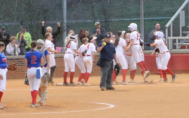 Press photo/Will Woolever. Junior Ashlyn McConnell (right) celebrates with teammates at home plate after belting a three-run home run versus West Henderson March 28.