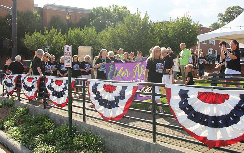 Press Photo/Shelby Powell - Macon County residents walk behind a banner to raise awareness for elder abuse.