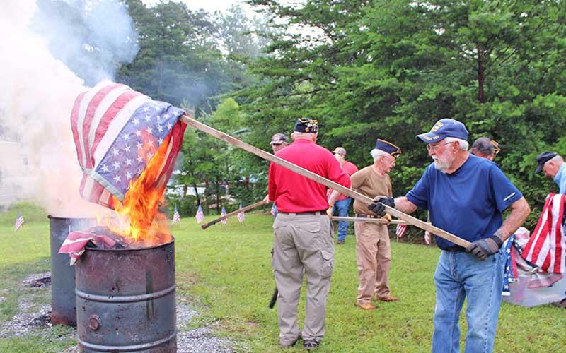 Press photo/Vickie Carpenter - Will Williams places a flag in one of the burn barrels during the American Legion’s flag retirement ceremony.