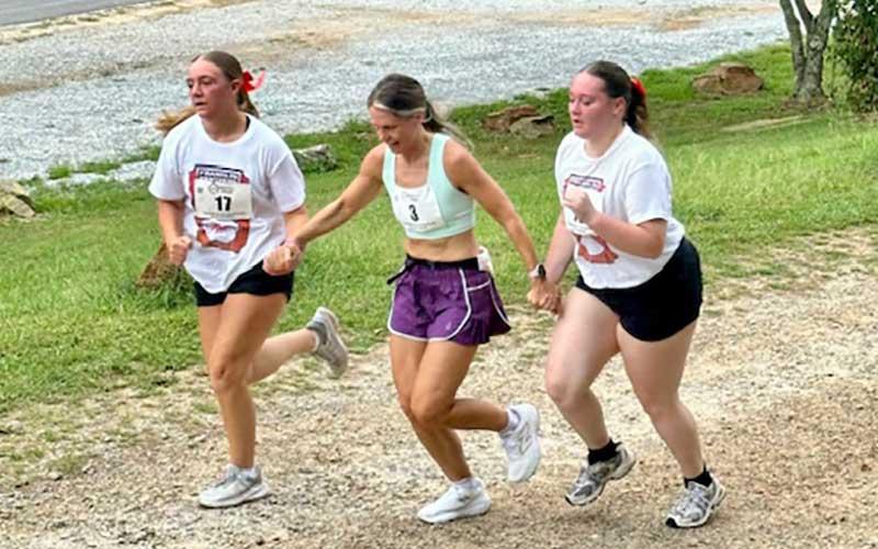 Photo submitted - (From left) Mariam Sanders, Lynn Baker and Mckinzy Carver run the 80s Flashback 5K through downtown Franklin Aug. 2. As part of their extensive community service efforts, team members who did not run the race volunteered to help administrate it.