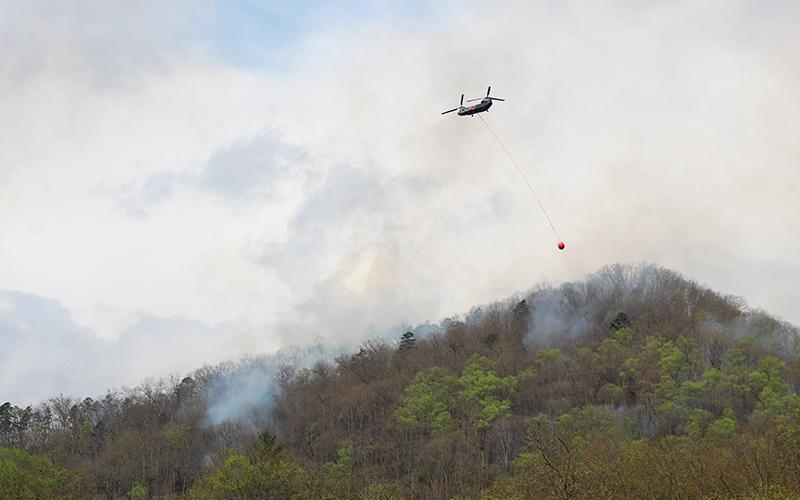 Press photo/Shelby Powell. A helicopter crew brings in more water to support ground operations in fighting a forest fire in the Needmore area on Friday, April 3.