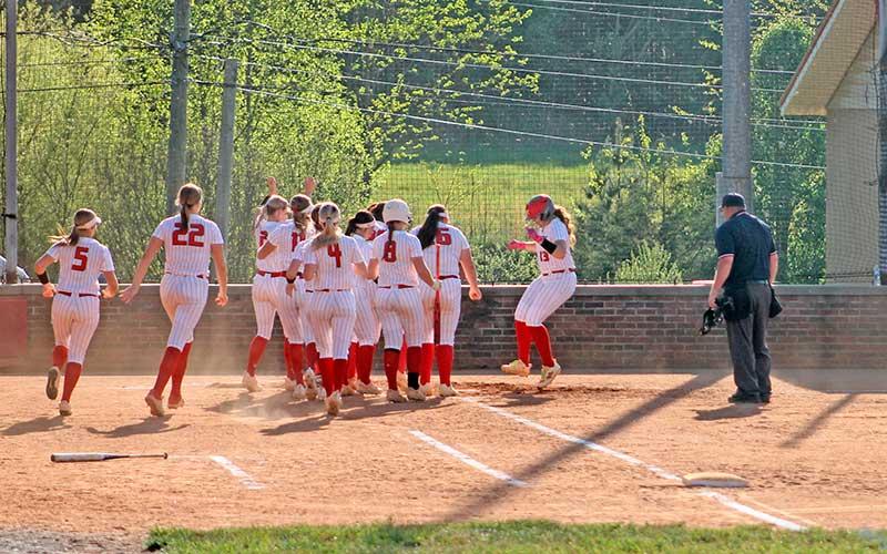 Meliah Mason (right) is mobbed by teammates at home plate after one of her two home runs versus North Henderson April 16. (Press photo/Will Woolever)