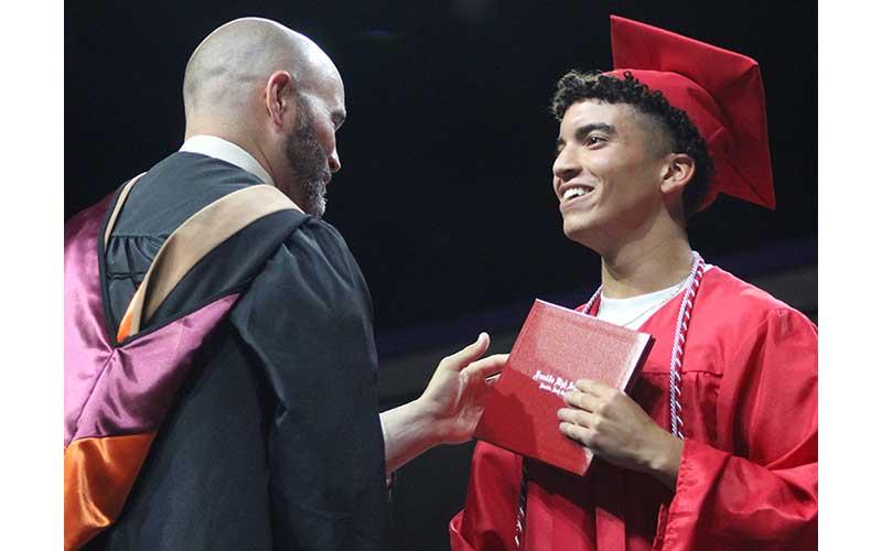 Press photo/Shelby Powell - Franklin High School graduate Samuel Roots accepts his diploma from Principal Blair King during the commencement ceremony June 5 at WCU. Roots wears a braided cord symbolizing his achievements in project management. See more photos on page on The Franklin Press Facebook page. 
