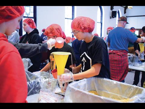 Press photos/Linda Mathias - Volunteers pack rice, soy, vegetables and vitamins for a Rise Against Hunger food packing drive at First United Methodist Church.