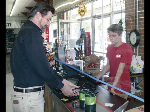 Liam Graham rings up Steve Wilcox’s purchase at Appalachian ACE Hardware from the other side of a sneeze guard.