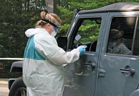 Photo/Ryan Hanchett A health care worker conducts a test for COVID-19 during drive-thru testing on June 4 in Highlands.