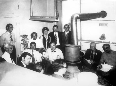 County commissioners and other local officials meet around a pot-bellied stove in the old courthouse in this photo from about 1970. That’s Dick Jones standing by the stovepipe, next to Sheriff George Moses. Press editor Bob Sloan is standing to the right of a poster for an Ox Roast Festival. County manager Ron Winecoff is in front of Sloan and County Chairman Oscar Ledford is sitting beside him. Also shown are the two other county commissioners and members of the Highlands town board. 