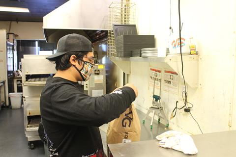 Press photo/Will Woolever - Papa’s Pizza To Go owner Eric Olvera opens a bag of flour while preparing for the day’s service. Olvera does not know whether Papa’s will be allowed to stay in its current location during renovations. 