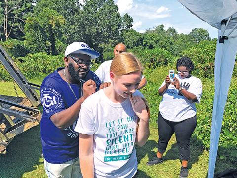 Allen W. Brown, a Christian rapper and evangelist, signs Carissa McGaha’s shirt during the Aug. 30 Save the Children event in Franklin. 