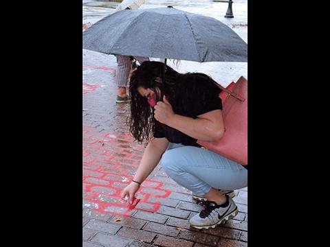 Press photo/Linda Mathias - Kuteka Lopez pours red sand outside the Macon County Courthouse to draw attention to victims of human trafficking.