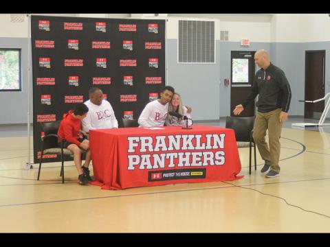Press Photo/Will Woolever FHS point guard chad Wilson hugs his mom, Stephanie Moore, after signing his official offer to Bryan College while Braeden and William Moore look on.