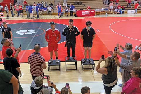 Press Photo/Will Woolever - FHS senior Branden Berger (center) stands on the podium after winning a Mountain Six Conference individual title. Berger will not wrestle at Regionals or State in order to attend basic training in the National Guard.