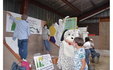 Press photos/Mia Overton - Volunteers with Appalachian Animal Rescue Center work on their booth at the Macon County Fair on Monday morning.
