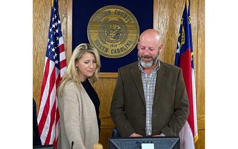 Press photo/Rachel Hoskins - Jim Tate’s wife, Allison, joined him at the podium to adjourn the Nov. 8 meeting of the Macon County Board of Commissioners. This was Jim Tate’s last official meeting as a board member and chairman.